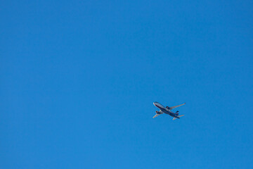 Flight of a white plane with the flag of Russia on a blue background