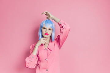 fashionable woman in blue wig pink dress red lips pink background