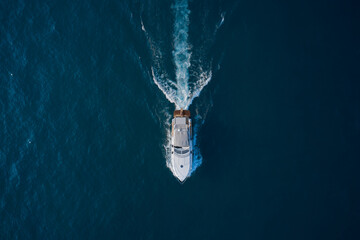 White yacht on the water top view. White boat with people on blue water aerial view. People in a...
