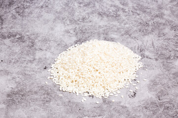 Pile of white rice grains on a gray stone background. Oriental food