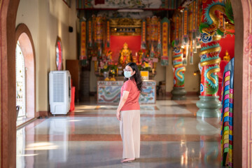 Portrait of asian woman traveler wear protective mask germs is praying at Chinese buddhist temple or shrine in Thailand,Prevention of the spread of COVID-19 virus,Chinese New Year