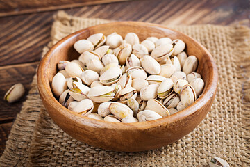 Pistachio nuts in shell  in bowl on wooden background.