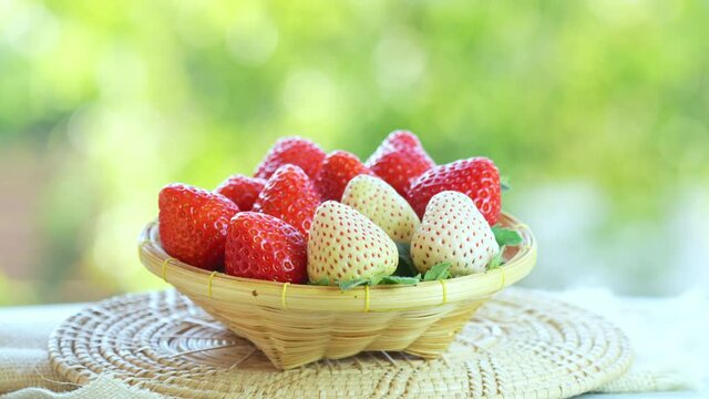 Fresh red and white strawberries in a wooden basket on wooden background, Red Strawberries and Pine berry or Hula strawberry in Bamboo basket