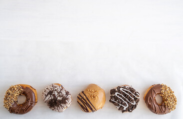 Fototapeta na wymiar Assortment of Chocolate Glazed Donuts on a White Table with Copy Space