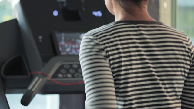 Woman running on the treadmill while watching the tv show on the tablet screen. An athletic doing exercise training for stamina and cardio at home.