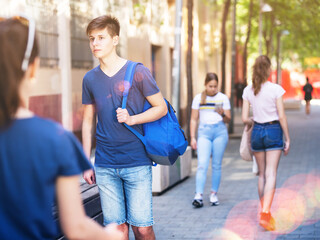 Positive teenager walking in the street, carrying a bag on one shoulder