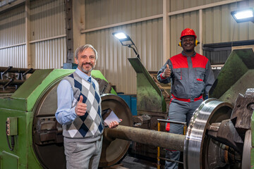 Production Manager And African American CNC Machine Operator Giving Thumbs Up In A Train Factory. Multiracial Industrial Co-Workers  Standing Next To Lathe Machine - Train Wheel Manufacturing.
