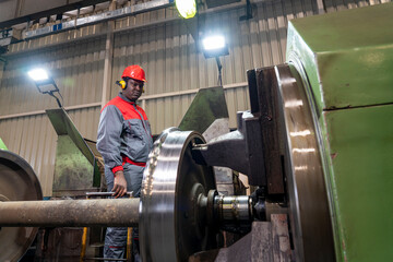 African Amererican CNC Machine Operator Monitoring The Train Wheel Manufacturing Process On Lathe Machine In A Train Factory