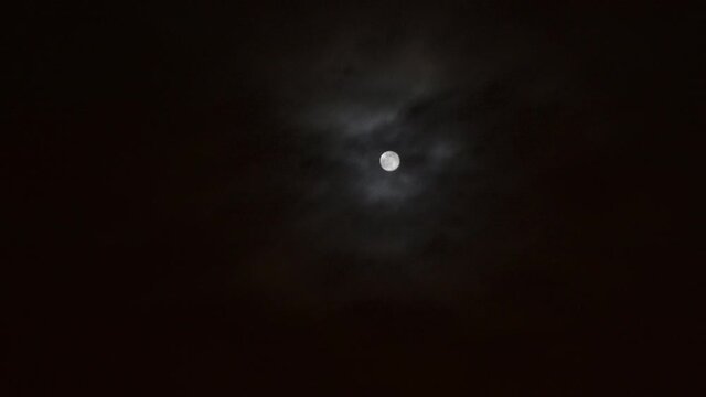 moon moving in and out of the clouds on a late evening where the weather is mysteriously changing to the creepy howls of an enchanted glowing where witches goblins and vampires lurk for their prey