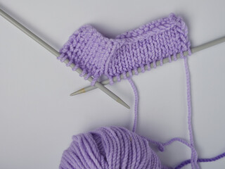 Wool yarn in different colors with wooden double point needles. The needles are being used for knitting socks, mittens or other projects joined in the round.