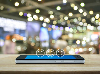 Excellent smiley face rating icon on modern smart mobile phone screen on wooden table over blur...