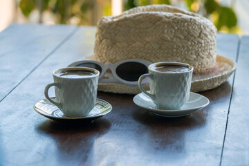 Two Cups of Freshly Brewed Coffee by the Straw Hat and White Sunglasses on the Table. Summer Vacation and Relaxation Concept