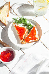 Sandwiches with red caviar on a white plate