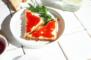 Sandwiches with red caviar on a white plate