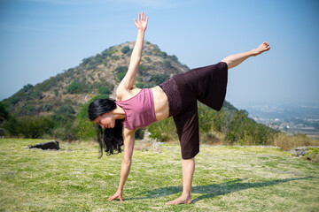 young woman performing the half moon pose, extremely difficult, training, yoga, mountains in the background, health, healthy, selective focus, defocused horizontal