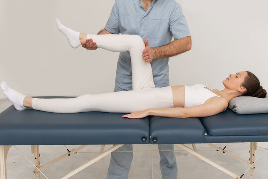 Knee pain relief in clinic. Doctor physiotherapist doing healing treatment on patient leg. Therapist giving leg and calf massage. Osteopathy, Chiropractic leg adjustment. Chiropractic treatment.
