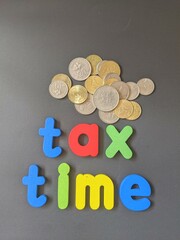 Picture of a coin with the word tax time on a black background