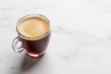 One glass coffee cup with espresso in morning on white marble background. Aroma, ristretto. Mug of coffee. Close up