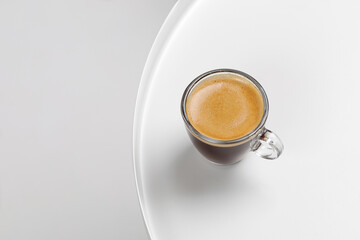 One glass coffee cup with espresso in morning on white table. Aroma, ristretto. Mug of coffee. Glass. Close up, top view