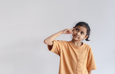 asian child girl wear orange T-shirt pointing to head gesture thinking. Thing ideas concept. Copy space use for text media advertise.