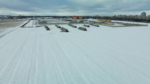 Flying over a snowy field. Straw bales are stacked. Traces of agricultural tillage are visible under the snow. Aerial photography.
