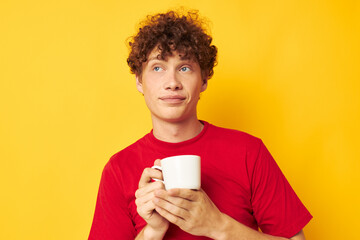 Young curly-haired man posing with a white mug and in the hands of a drink Lifestyle unaltered