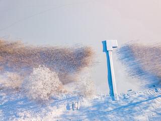 Aerial view of frozen lake and a footbridge covered in snow