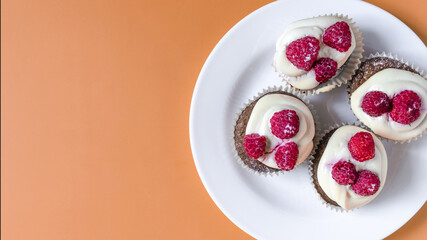 Homemade cupcakes with white cream and berries on a colored background. Sweet cupcakes on a bright background top view is a place for text.