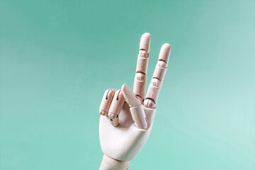 A wooden hand with the index and middle fingers raised up on a light background. A conceptual...