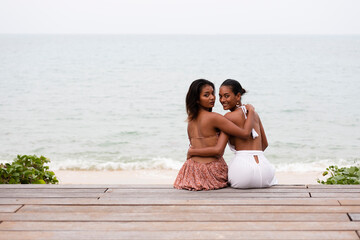 Fototapeta premium Two LGBT tanned women wearing casual dresses enjoy and feel happy at the white sand beach on Koh Samui, Thailand.