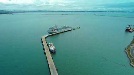 Aerial view over Argus Royal fleet auxiliary British military floating hospital ship docked at harbour breakwater