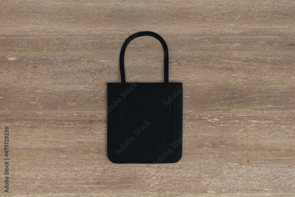 Aufkleber Top view and close up of empty black shopper on wooden table background. Mock up, advertisement, 3D Rendering.