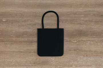 Fototapeta premium Top view and close up of empty black shopper on wooden table background. Mock up, advertisement, 3D Rendering.