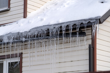 Icicles onroof of private house resulting from improper construction of roof. Metal Downpipe...