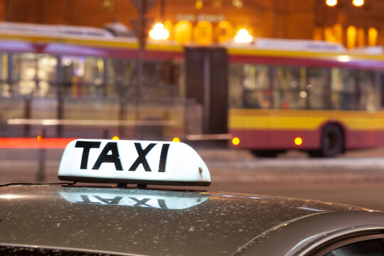 Shining Taxi inscription against passing cars on night street of big cit