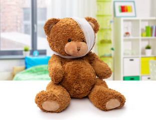 medicine, healthcare and childhood concept - teddy bear toy with bandaged head having toothache over children's room at home background