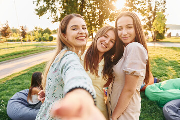 Naklejka premium Female friends standing and having fun. Group of young people have a party in the park at summer daytime