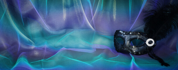Obraz na płótnie Canvas Photo of elegant and delicate Venetian mask over blue dark chiffon background