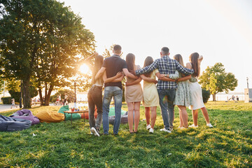 View from behind. Group of young people have a party in the park at summer daytime