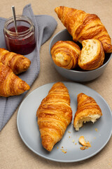 Croissants in gray plate and bowl. Jar with jam on gray napkin.