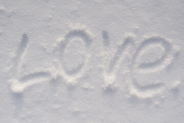 The inscription love is written on white snow. Flat lay, romance concept