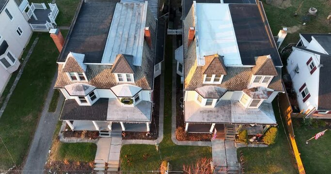 Aerial tilt up reveal of homes in neighborhood community in USA. Small town America during golden hour light.