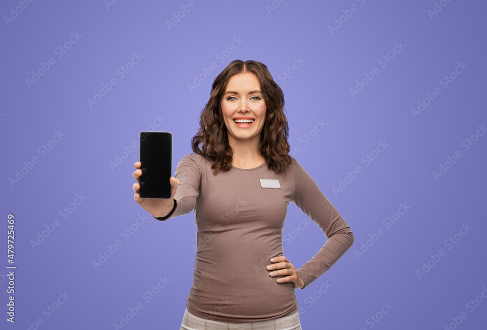 Poster sale, shopping and business concept - happy female shop assistant with name tag showing smartphone o