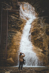 tourist photographs waterfall, man and waterfall.