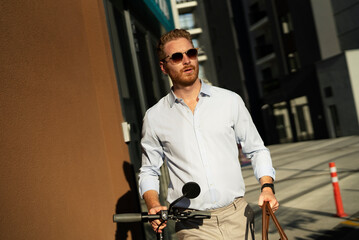 Fototapeta na wymiar Young stylish businessman with e-scooter. Portrait of handsome man outdoors