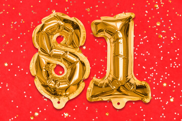 The number of the balloon made of golden foil, the number eighty-one on a red background with...