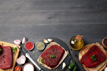 Concept of cooking with raw beef steaks on dark wooden background