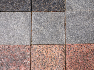 Background of the pavement lined with granite slabs close up. Surface of rocks contain corrosion...