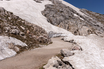 Narrow sidewalk through the snow and scree of the mountains