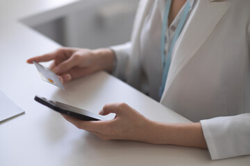Cropped image of a female holding smartphone and credit card.